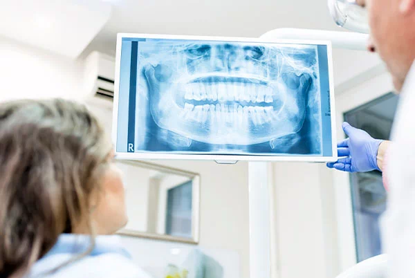 stomatolog przedstawiający kobiecie zdjęcie rentgenowskie